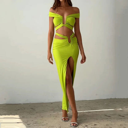 Woman wearing a bright green off-shoulder dress with a high slit on a plain background