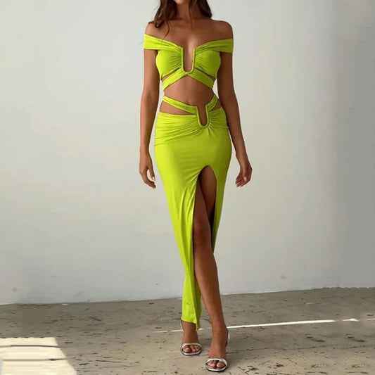 Woman wearing a bright green off-shoulder dress with a high slit on a plain background