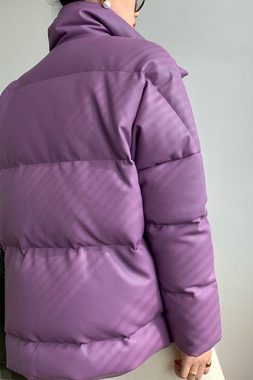 Purple puffer jacket worn by a person against a plain background