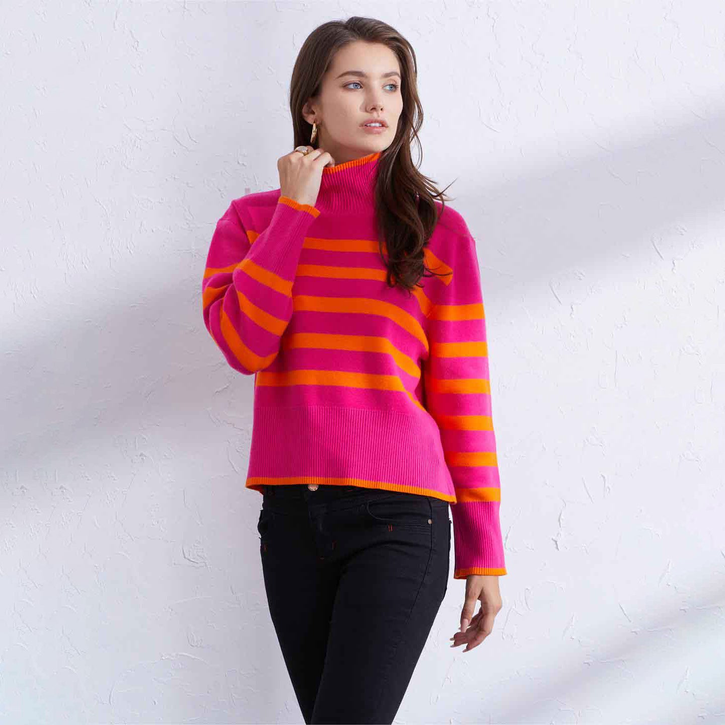 Woman wearing a pink and orange striped sweater against a white background