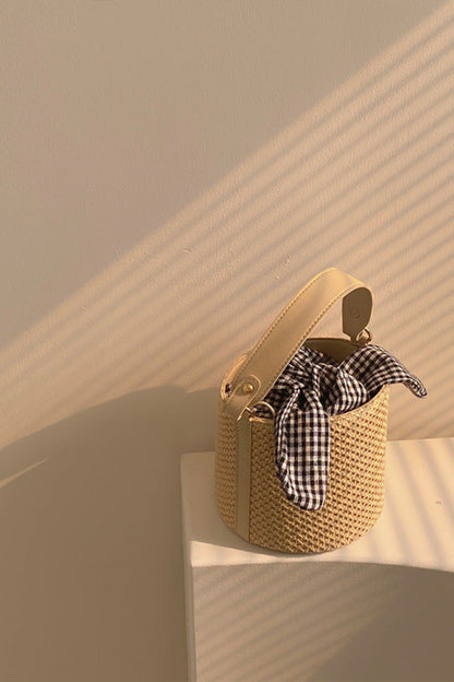 Woven handbag with a checkered scarf on a beige background