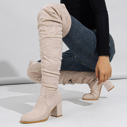 Beige knee-high boots worn by a person on a light gray background